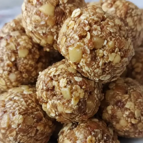 A stack of peanut butter oat energy bites in a speckled ceramic bowl, studded with visible oats and chia seeds.