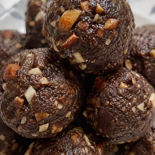 A stack of no bake peanut butter oat energy bites in a speckled ceramic bowl, studded with visible oats and chia seeds.