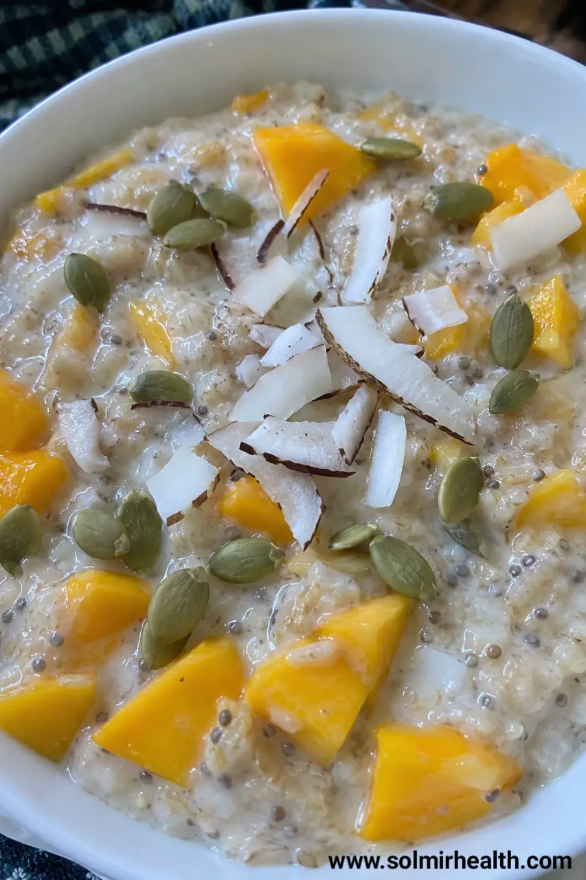 A jar of coconut oats topped with diced mango and shredded coconut.