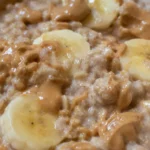 A bowl of oatmeal topped with banana slices and a drizzle of peanut butter. oats recipes