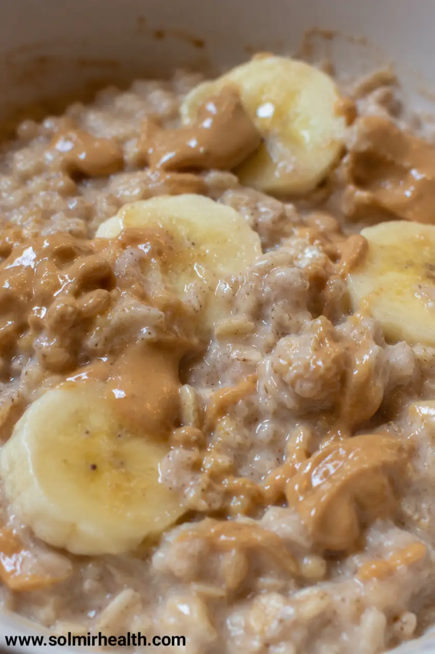A bowl of oatmeal topped with banana slices and a drizzle of peanut butter. oats recipes