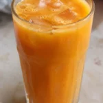 Golden carrot orange turmeric juice in a glass with ice
