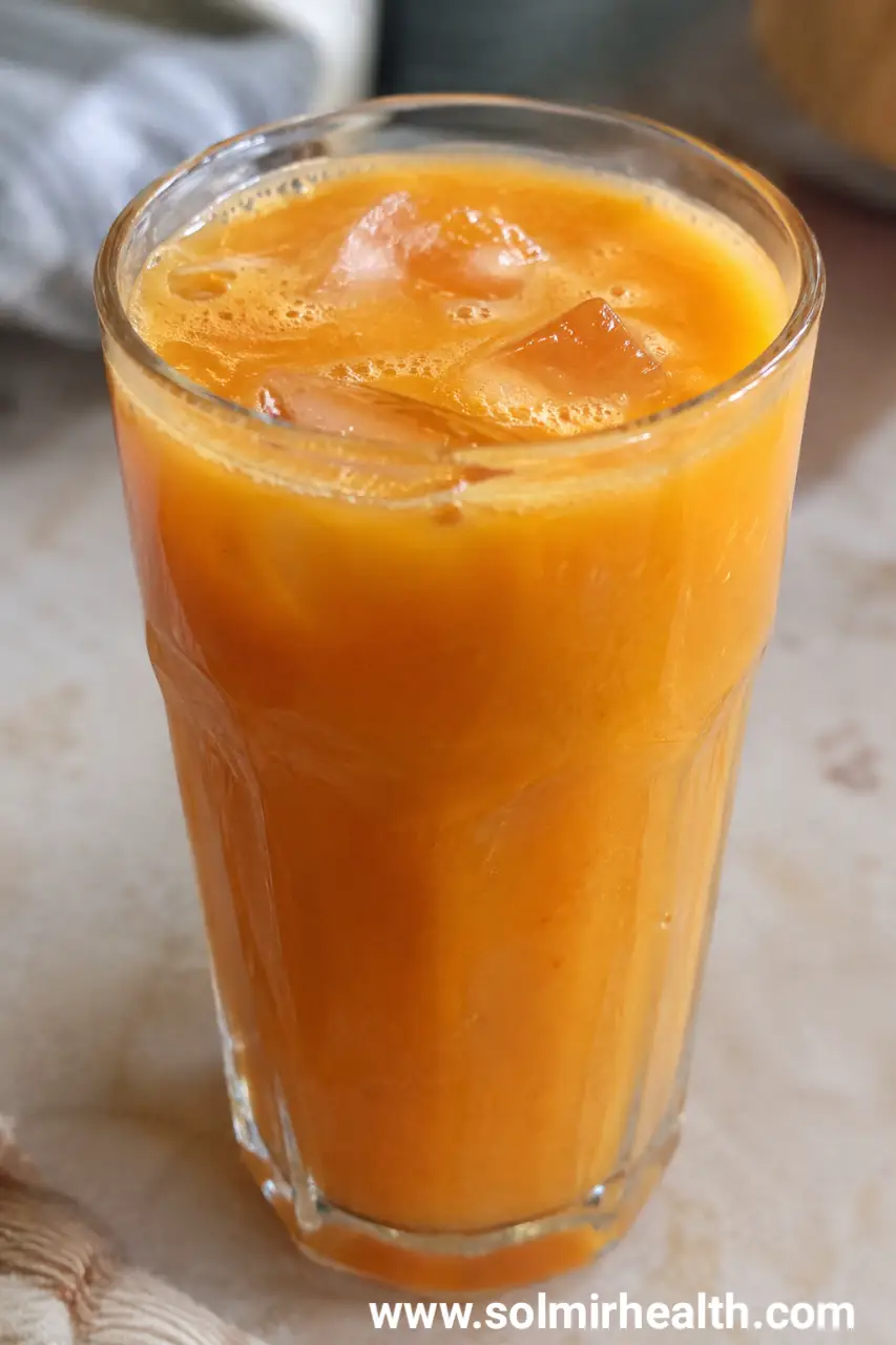 Golden carrot orange turmeric juice in a glass with ice
